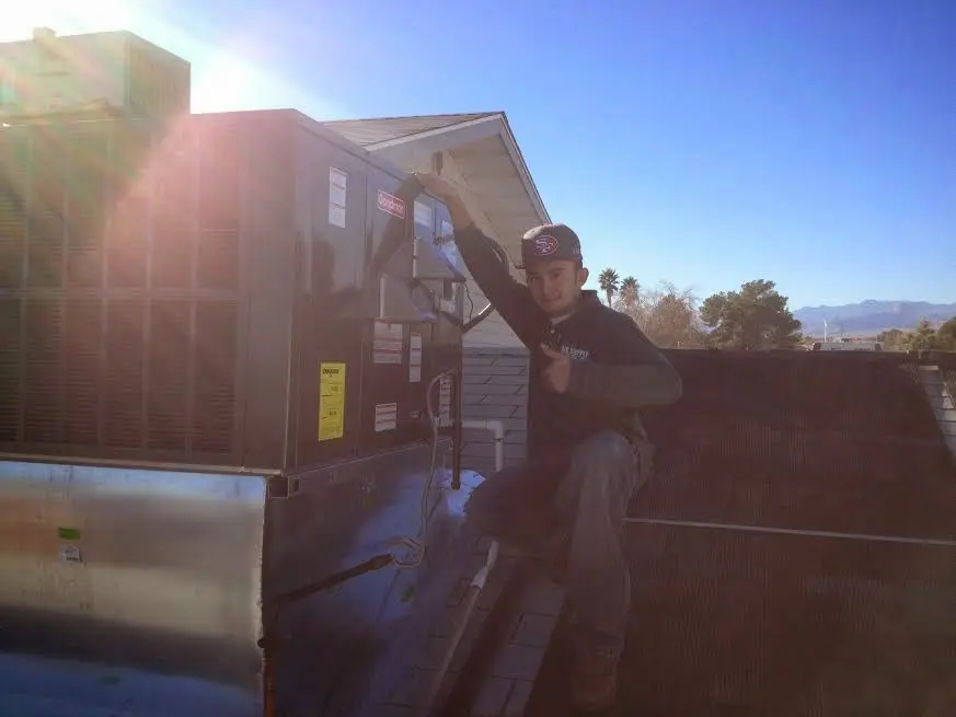 HVAC technician performing AC Tune-Up on a rooftop unit in West Bountiful